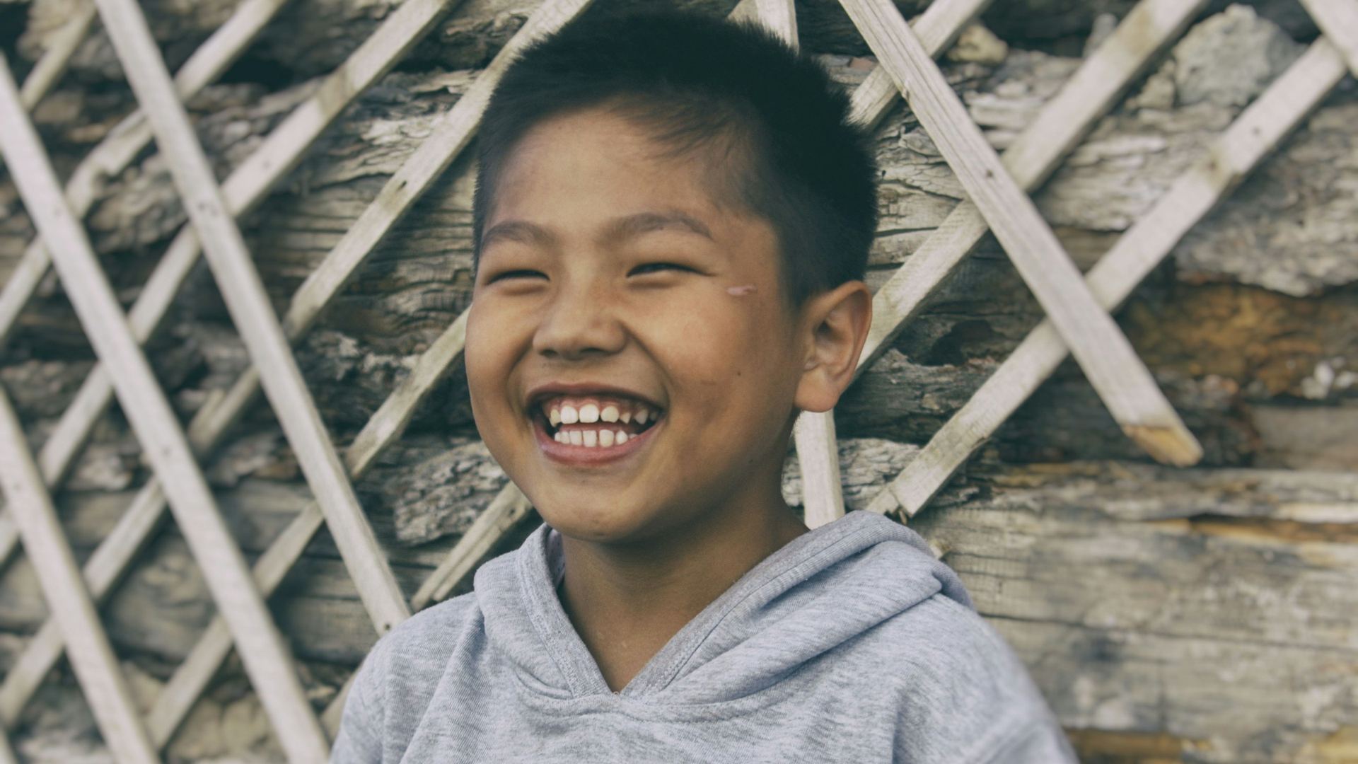A smiling boy in a gray hoodie