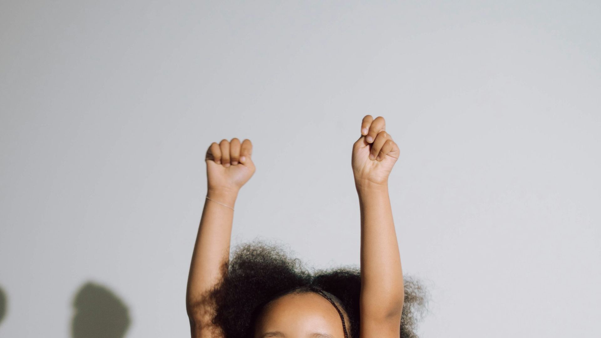 A joyful girl raises both arms in celebration