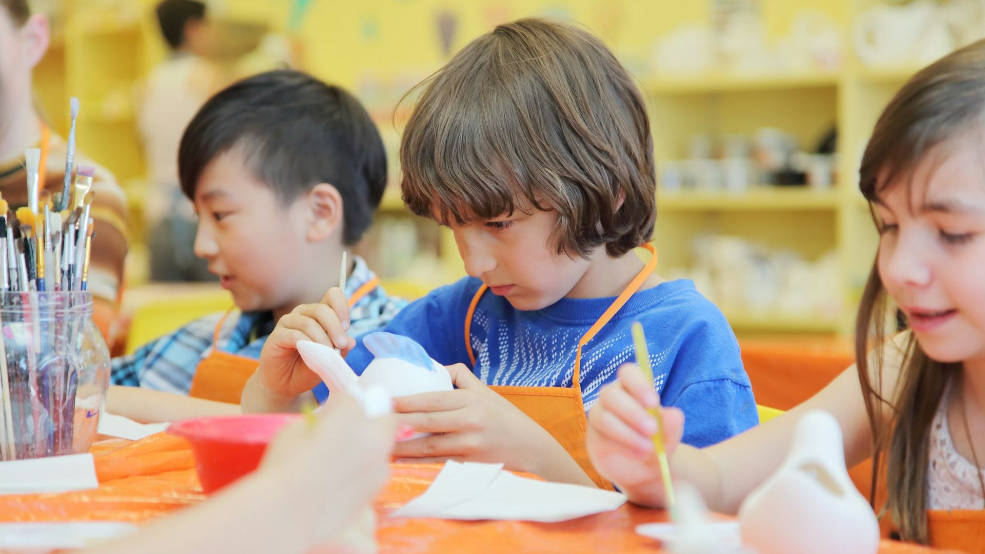 Children work on art projects around a classroom table