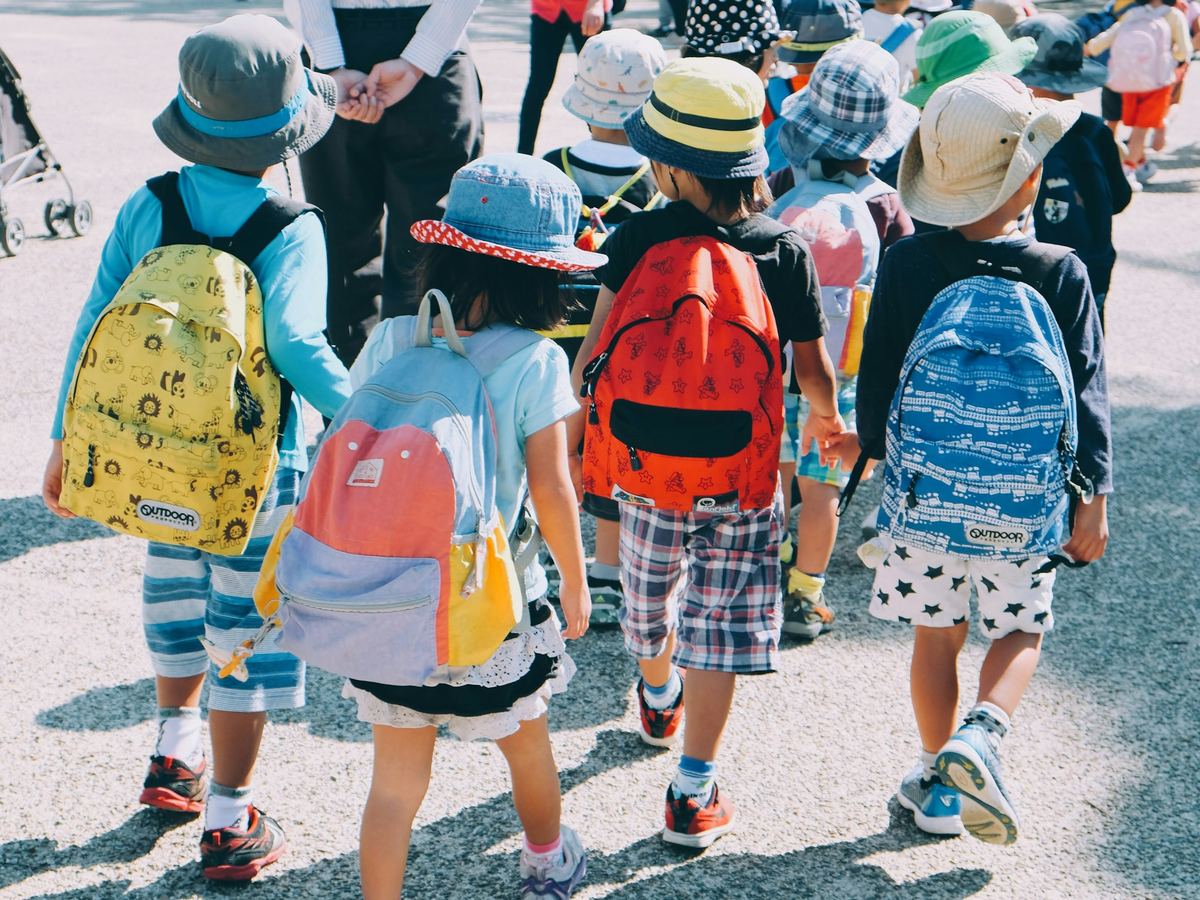 Children with colorful backpacks walk to school together